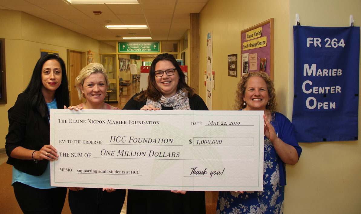 Pathways coordinator Irma Medina, HCC students Savannah Vezina of Agawam and Nicole Haswell of Chicopee, and Marieb Adult Learner Success Center coordinator Lori Wayson hold a ceremonial check for $1 million from the Elaine Nicpon Marieb Foundation outside HCC's Marieb Center. 