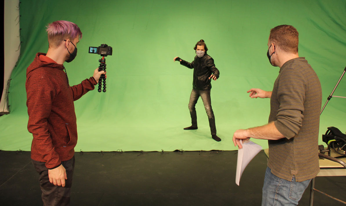 HCC theater professor Tim Cochran, right, directs a fight sequence with alumni actor Mike Pray for the HCC production of Fatal Fisticuffs, as streaming coach and HCC alumnus Cory Missildine, left, records. 