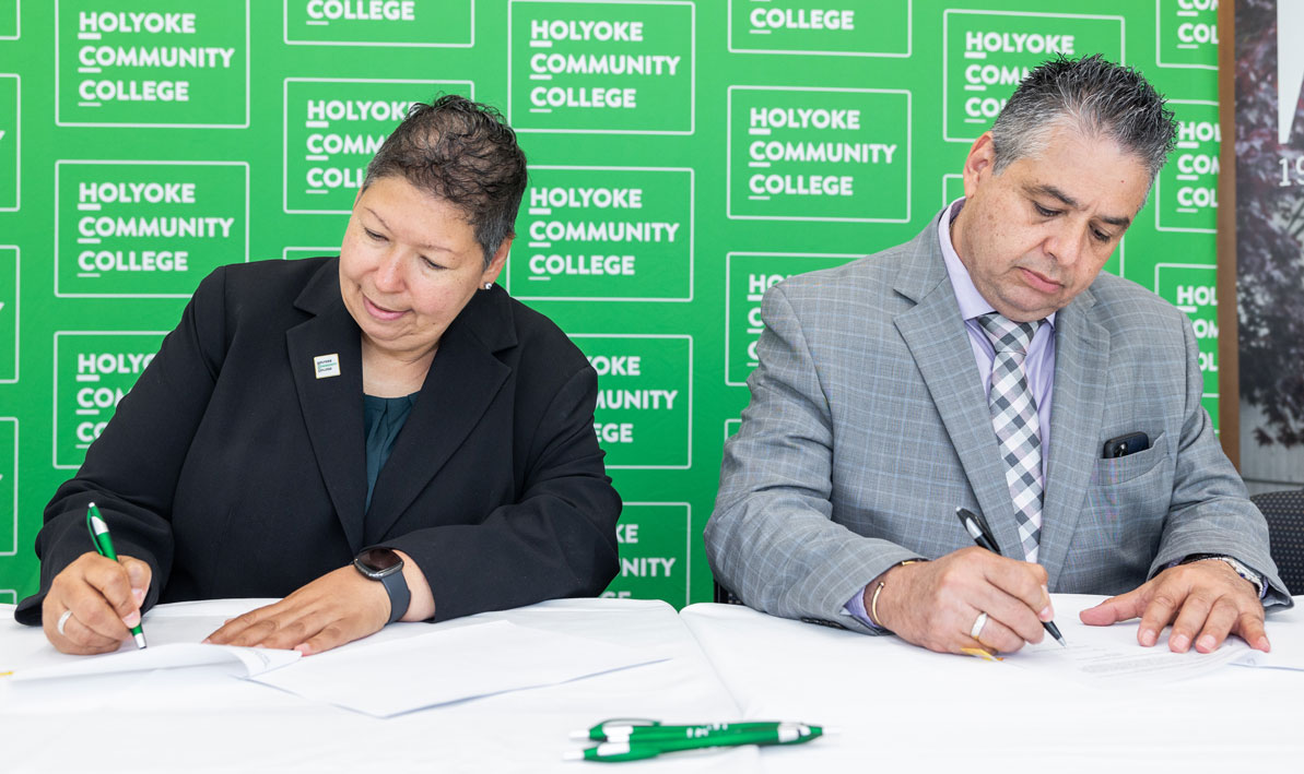 HCC president Christina Royal and AIC president Hubert Benitez sign an agreement between the two colleges. 