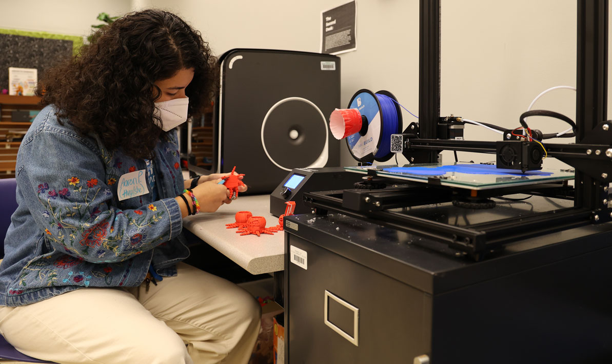 Aaron Portillo '22, an HCC STEM peer mentor and tech specialist, works on a 3-D printed pumpkin (with legs) in the STEM Innovarion Lab at HCC during STEM Week. 