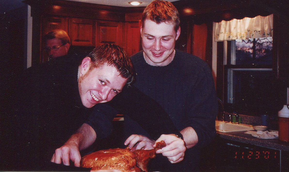 Timmy Thompson, left and his brother Chris carve a turkey