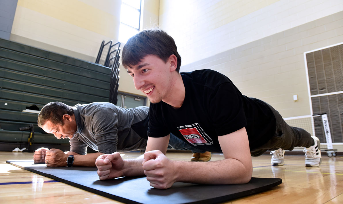 HCC criminal justice student and teacher Alex Sanchez test their abdominal endurance during a fitness test.