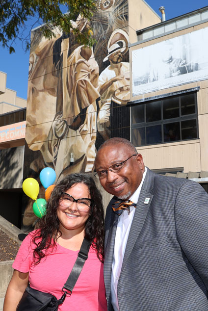 Muralist Betsy Casañas and HCC President George Timmons stand in front of one of HCC's three new murals.