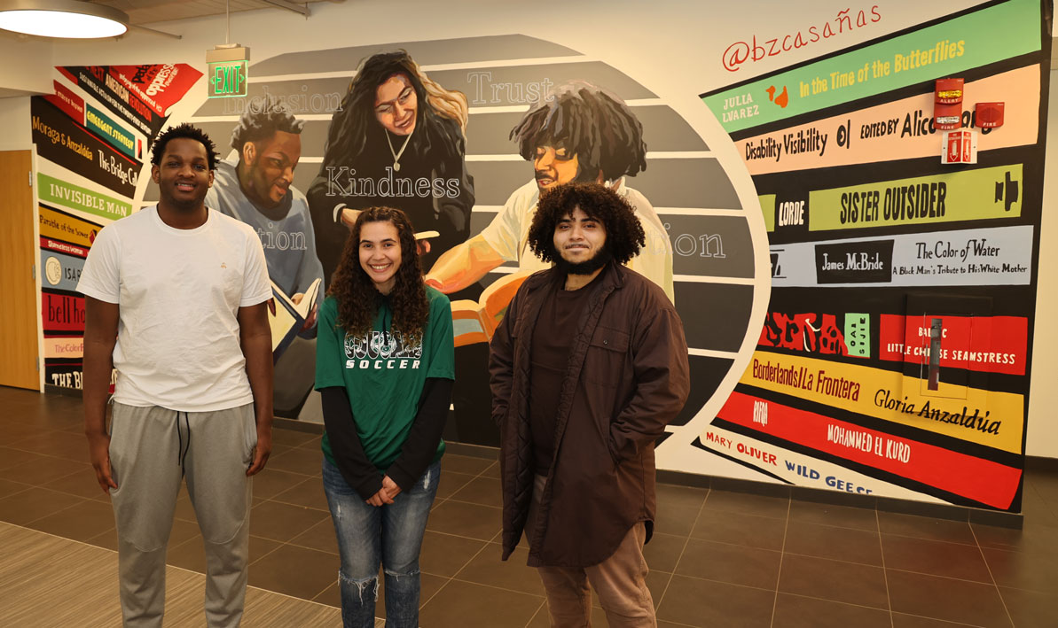Tahir Bey, Carineh Sanatana, and Arnaldo Lassend stand in front of the new campus mural that bears their likenesses. 