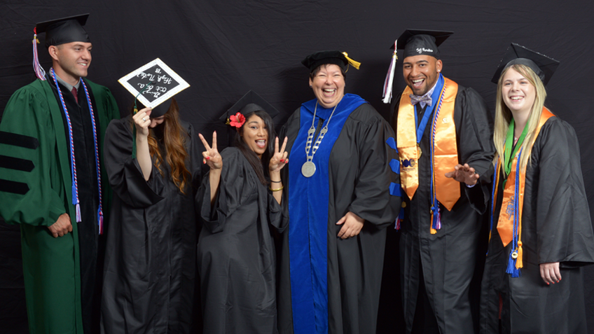 A photo of Christina Royal posing with a group of HCC graduates at Commencement