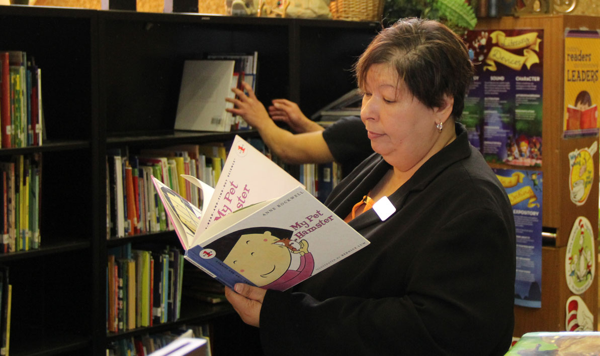 HCC president Christina Royal browses a book in the Kelly Elementary School library.