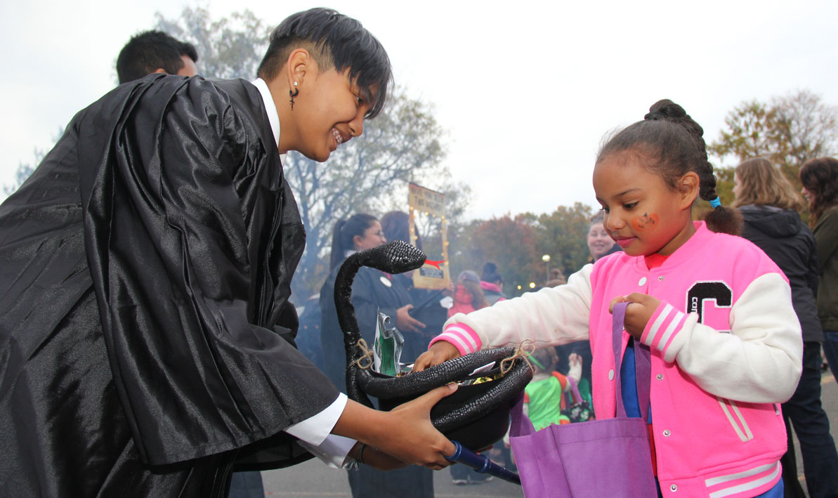 An HCC student dressed as a wizard from Hogwarts hands out candy to a child at HCC's Trunk or Treat celebration in 2019.