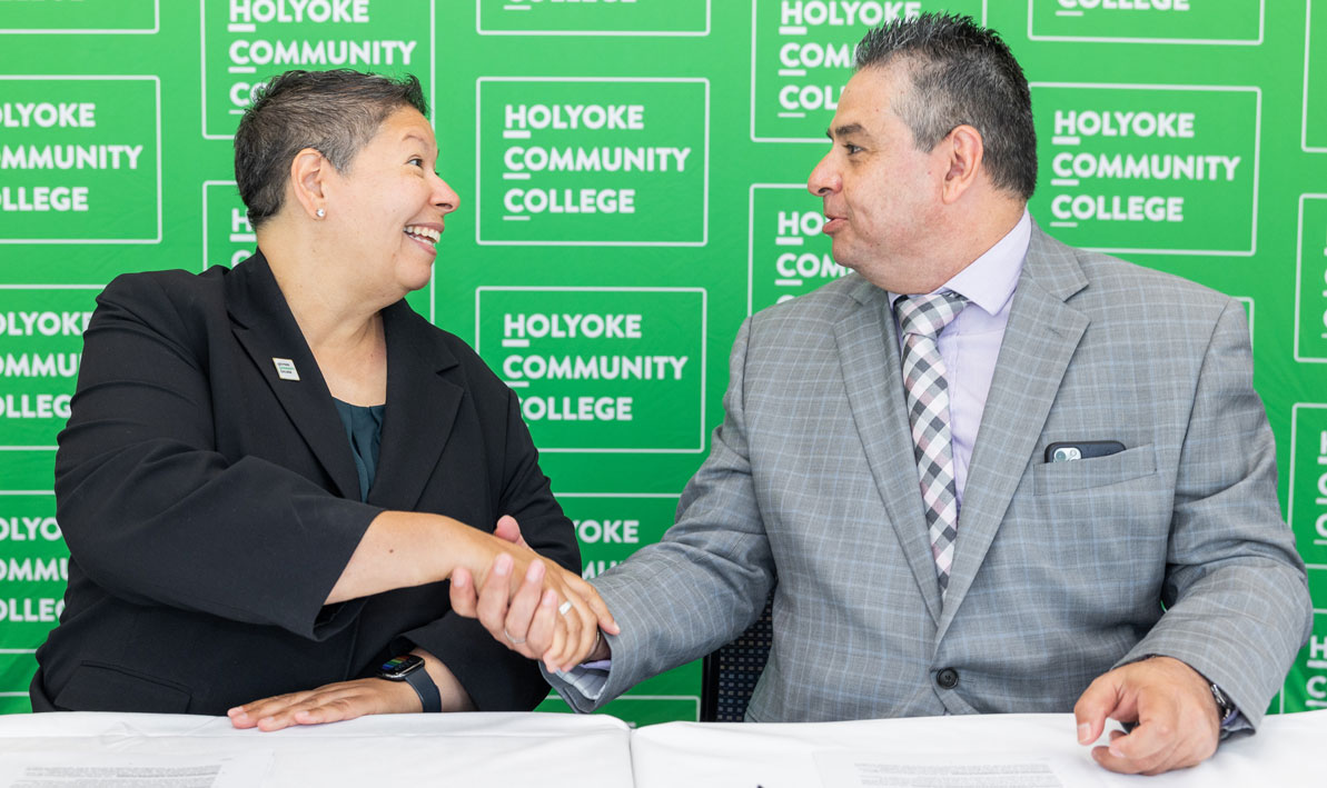 HCC president Christina Royal shakes hands with AIC president Hubert Benitez at  June 23 signing at HCC.