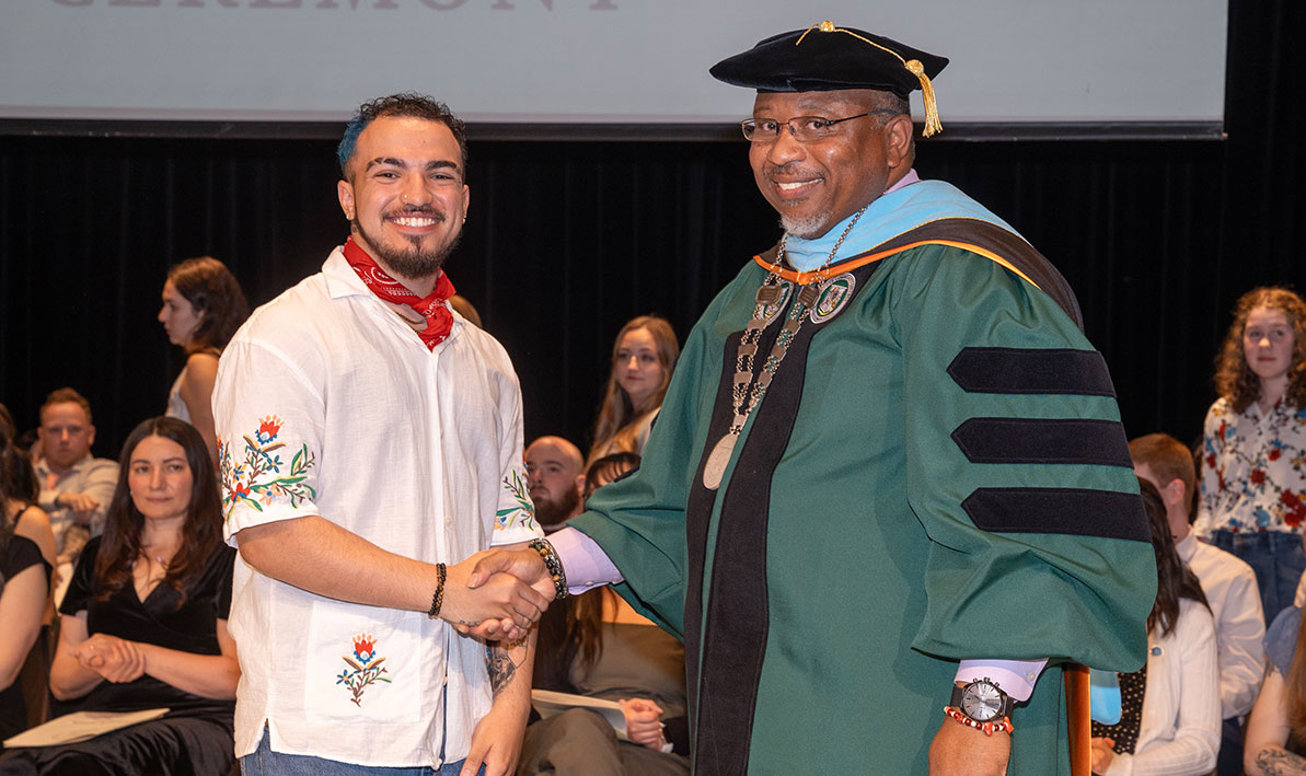Award recipient Johnny Garcia '24 shakes hands with President George Timmons.