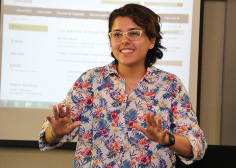 A student wearing glasses speaks in front of class