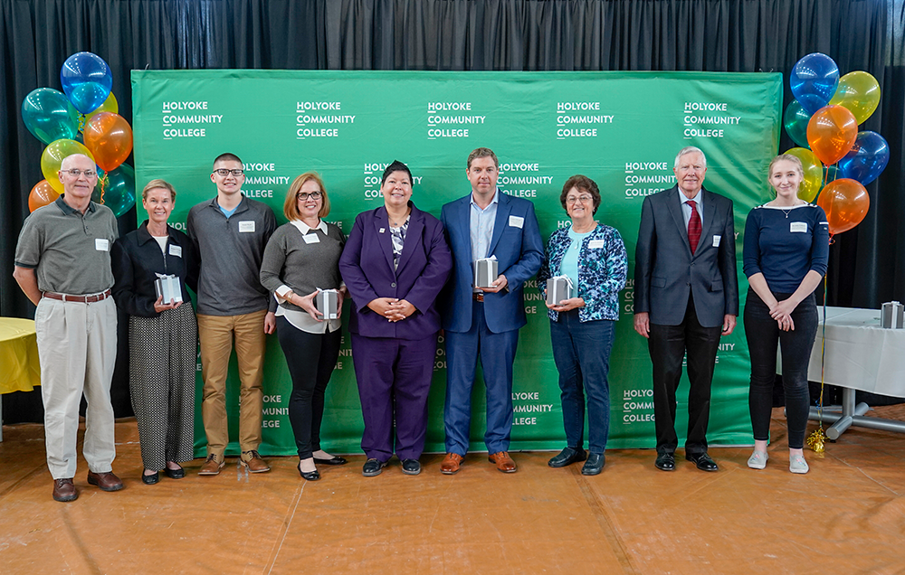 Group photo of individuals at the 2019 scholarship reception posing in front of a green HCC backdrop