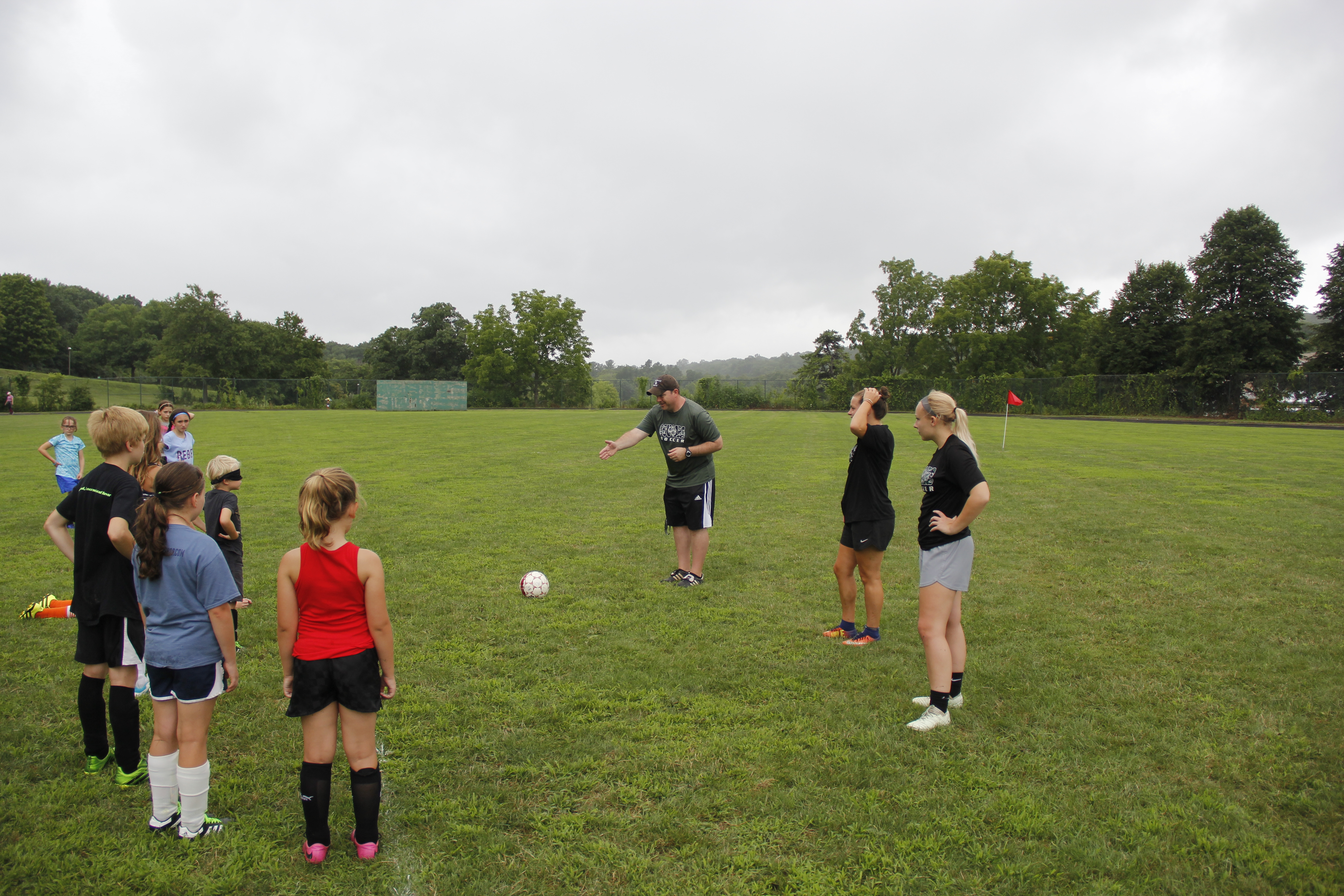 A soccer coach instructs students standing on a field
