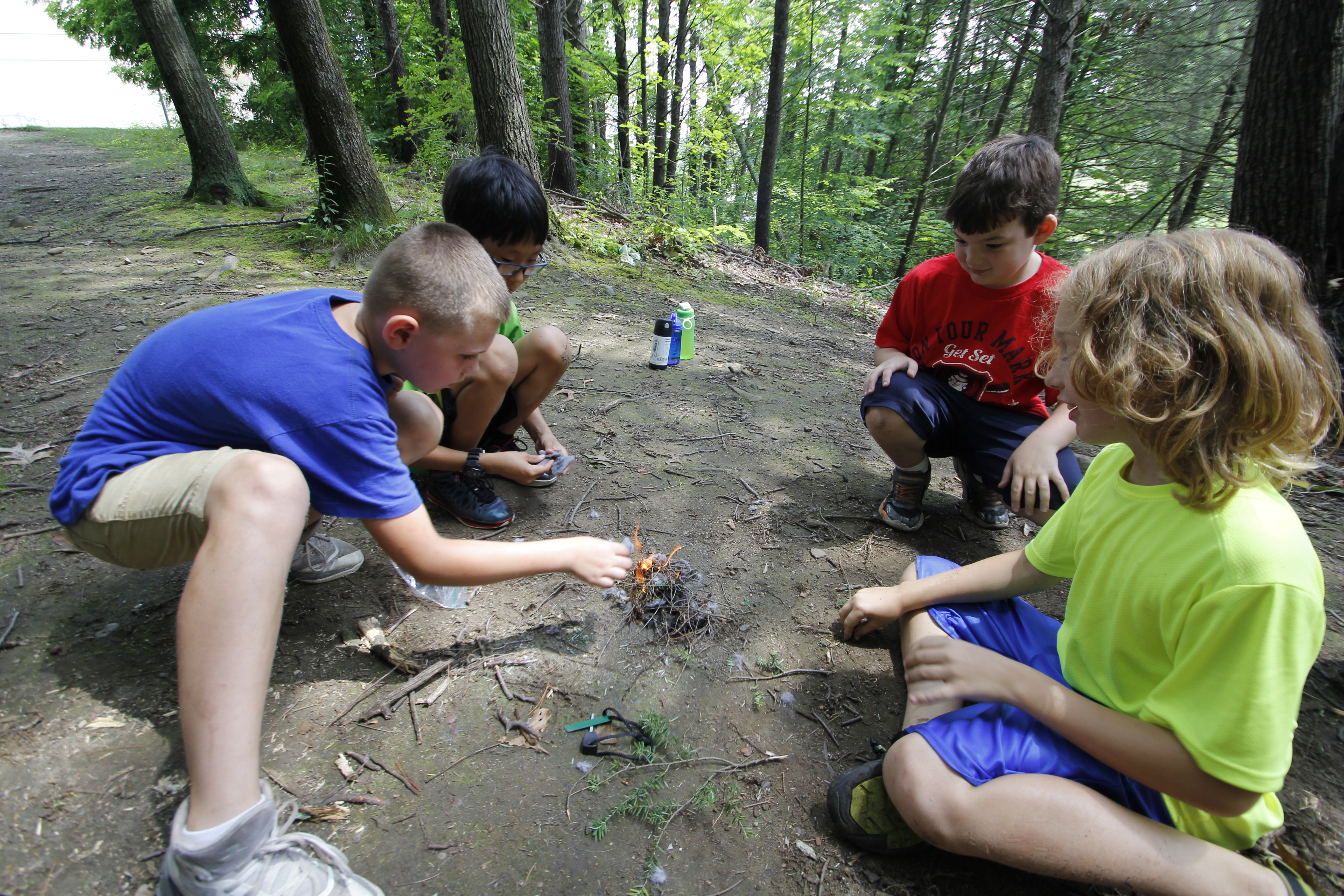 Four children start a campfire in the woods