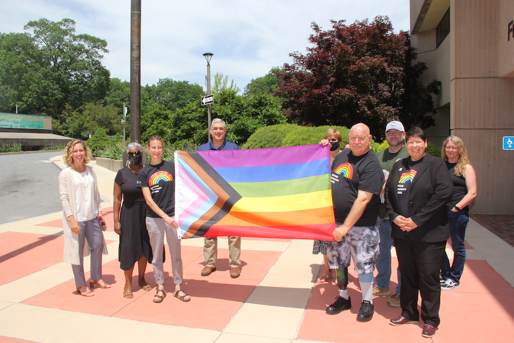 A group of people posing and displaying the Pride flag at the HCC bus circle
