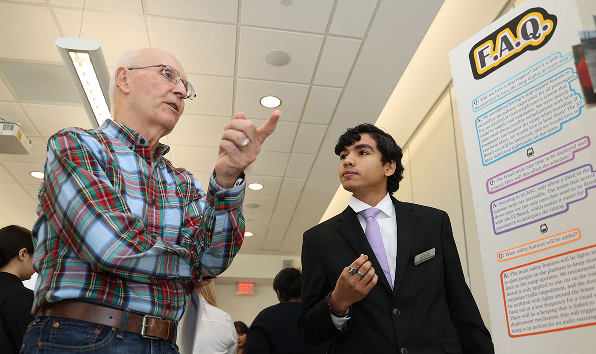 Innovation Challenge judge Ed Germain '71 talks to student Eithan Ortiz Viera about his team's EZ Board idea.