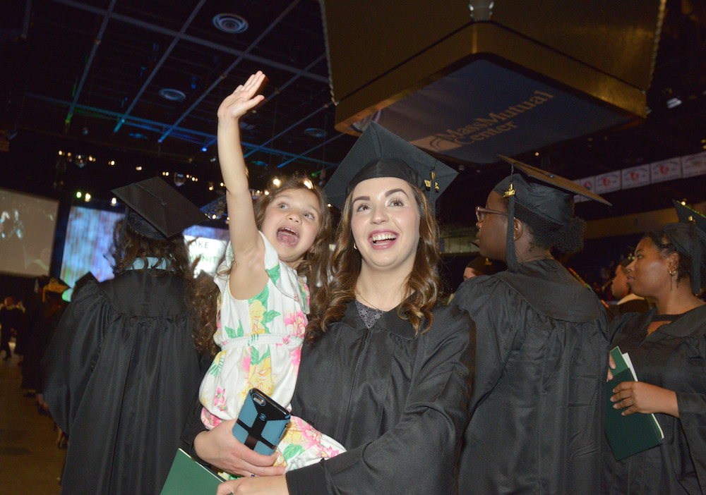 A graduating student with a child in her arms