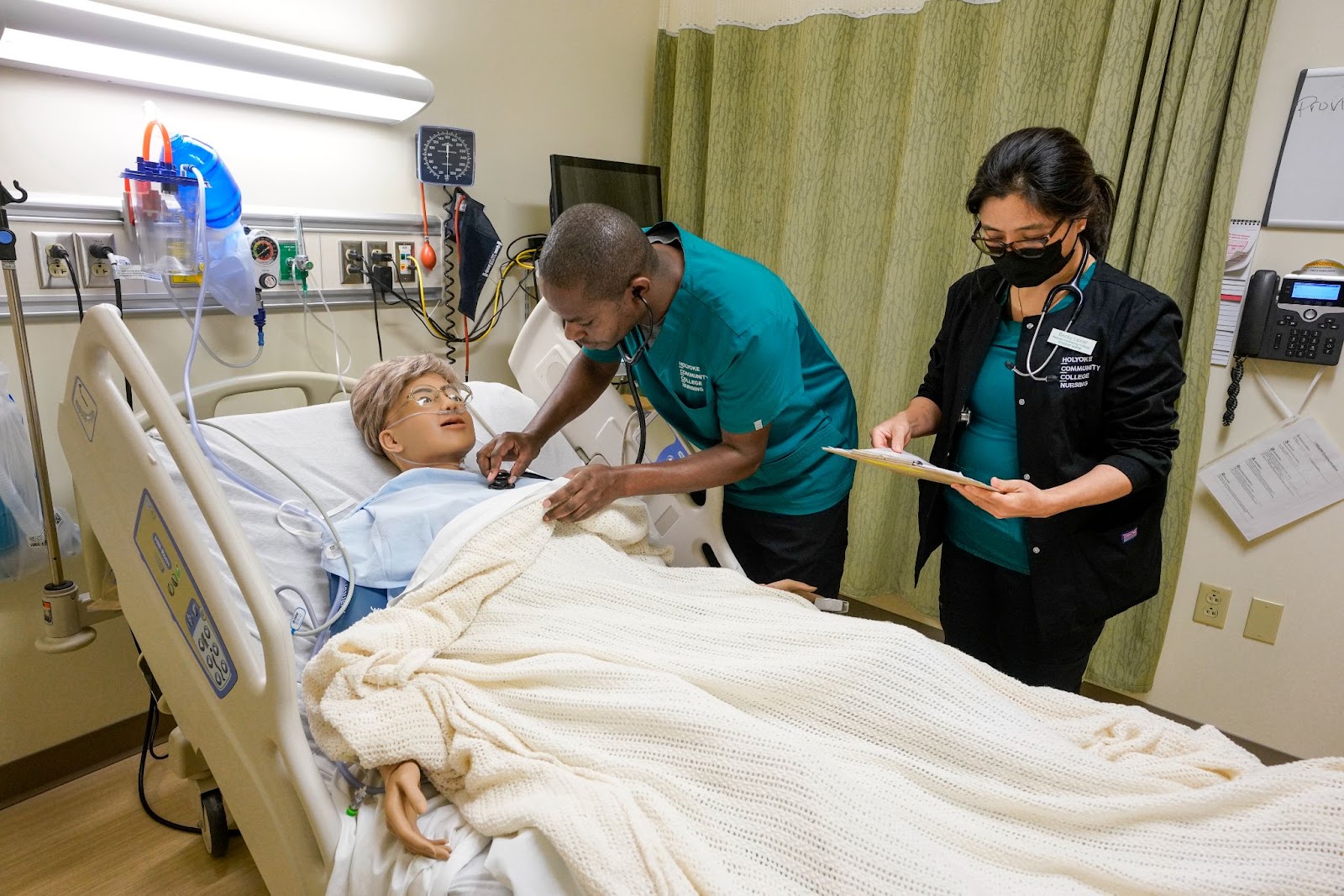 A medical student examines a patient simulator with an instructor